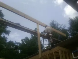 Carpenter setting a ridge beam over a new addition frame — Ice Dam Removal by Roofing Brothers in Weston